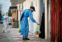 A volunteer provides food to a child in a residential neighbourhood