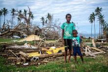 Two boys in front of the remains of a house. 