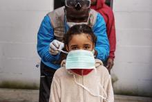 A health worker checking tying her facemask.
