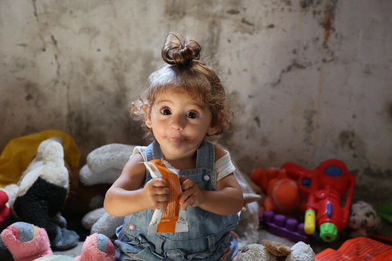 syrian baby eating from nutrition packet