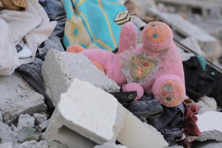 a child's plush toy amid rubble