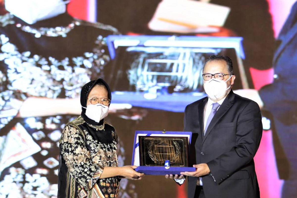 A man and a woman hold up an award on stage.