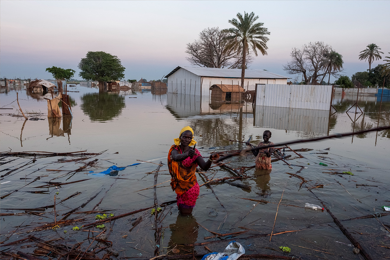 Una mujer andando en una aldea inundada por el agua
