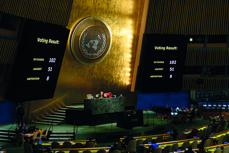 View of the General Assembly hall, where two people are seated at the podium, in front of a gilded wall. On either side, two screens show the results of a vote held there: 102 votes in favor, 51 against and 8 abstentions.