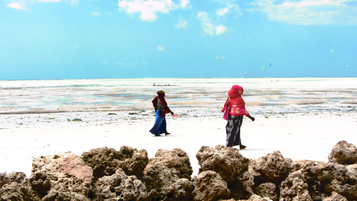 Two women walk along a beach