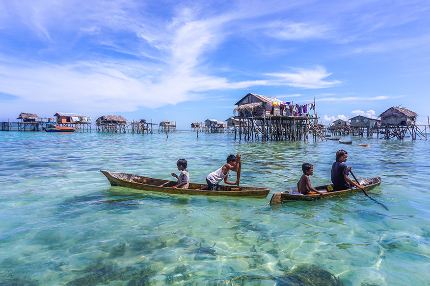 children in boats among houses on water