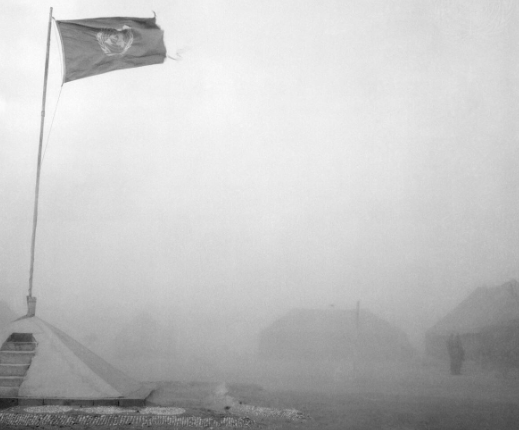 a black and white photo of a flag fluttering in a sand dust storm