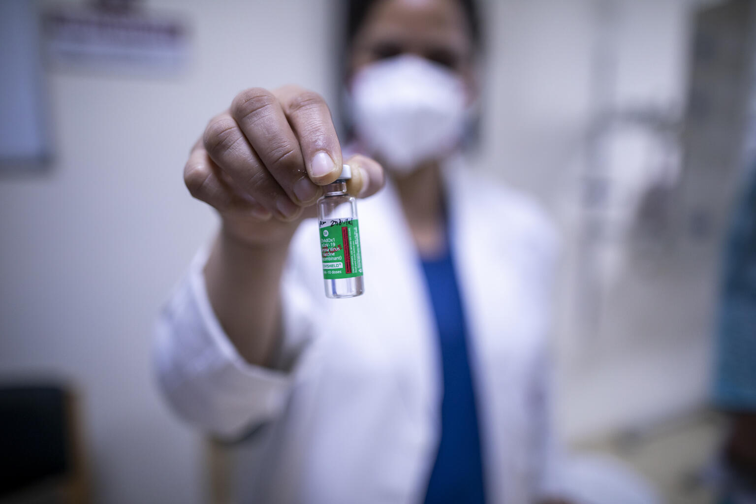 medical worker holding up vaccine vial