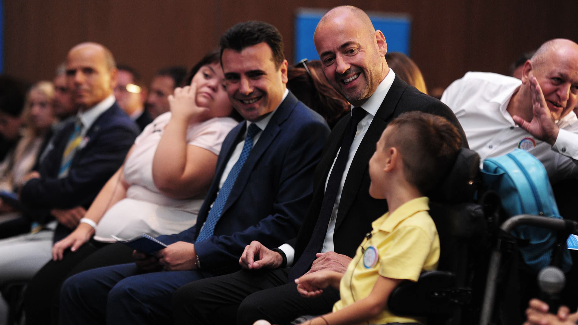 Benjamin Perks and Prime Minister of North Macedonia sitting in audience with a child in a wheelchair