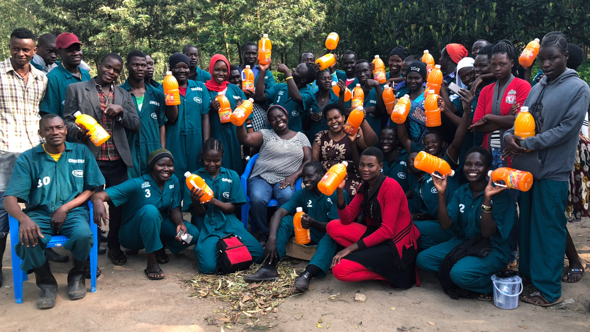 A group poses for a photo holding out orange juice jugs.