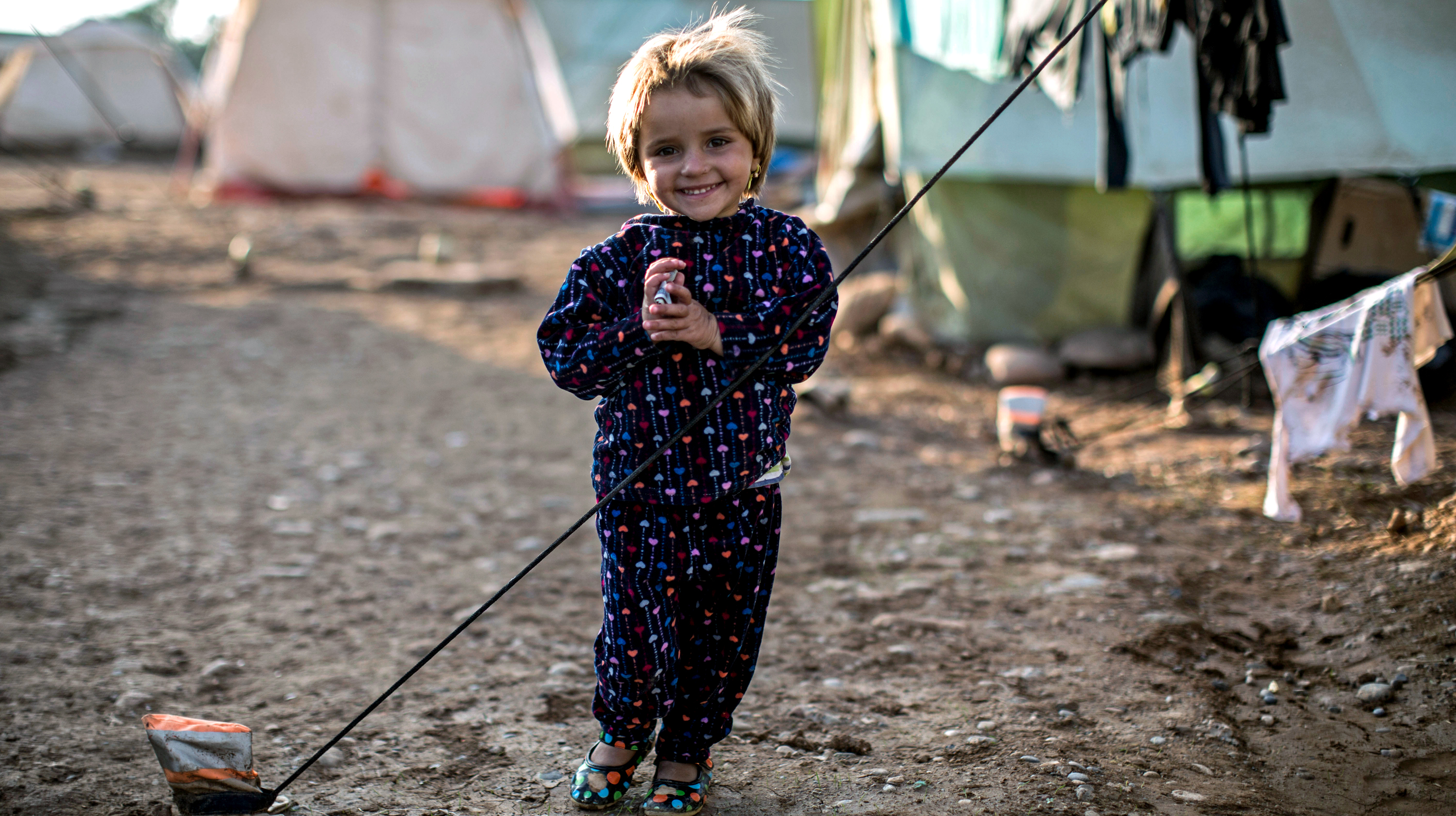 A young girl stands by her tent