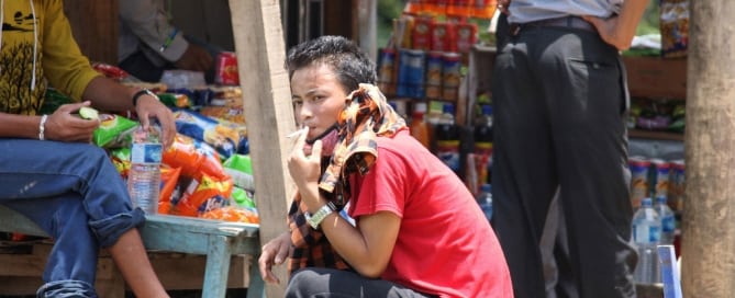 A man smokes a cigarette at a road side rest stop in rural Nepal