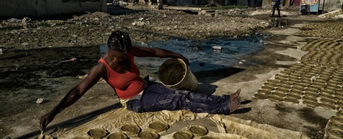 A woman working for a collective prepares “clay cakes,” sun-baked disks of clay, butter and salt, which have become a symbol of Haiti’s struggles with extreme poverty and hunger.