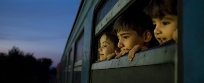 Photo: Children look out a train window at a reception centre for refugees and migrants in the former Yugoslav Republic of Macedonia.