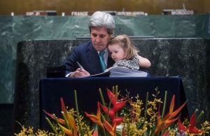 Photo: US Secretary of State John Kerry signs the Paris Agreement with his granddaughter on lap.