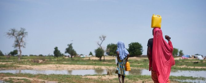 Photo: Girls carry water through a field after rain at a site of displaced civilians in Diffa, Niger, on 18 August 2016.