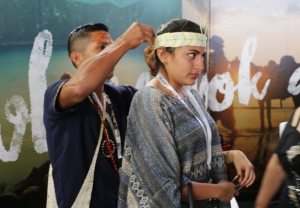 Photo: A man ties a headband on a Habitat 3 participant in the Ecuador Pavilion.