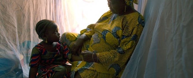 امرأة مع طفلها تحتمي بخيمة مصممة لتقي من الحشرات الناقلة للملاريا