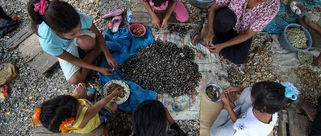 Una familia comiendo en el suelo. Foto OIT/Ferry Latief