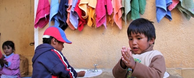 Dos niños se lavan las manos con jabón.