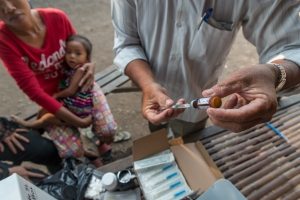 Un professionnel de santé se prépare à administrer un vaccin à un enfant dans une unité de vaccination mobile, dans le village de Svay Pak, au Cambodge. Photo UNICEF/Llaurado