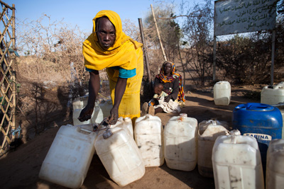 Enero de 2014. Los desplazados internos en el campo de Nifasha en el norte de Darfur tienen acceso a agua únicamente durante dos horas por la mañana, lo que no deja suficiente tiempo a todos para abastecerse. Una mujer deja una fuente de aprovisionamiento de agua con sus garrafas vacías justo después de que termine la hora de abastecimiento. Foto ONU/Albert González Farran