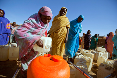 Women filling an orange Water Roller at a water distribution point in the Abu Shouk Camp for internally displaced people. UN Photo/Albert González Farran 