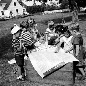 联合国国际育童学校的孩子们正在观看一张《世界人权宣言》的海报，摄于 1950年。 联合国图片