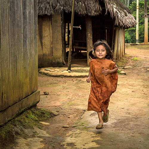 在秘鲁潘戈阿地区，一个小女孩跑过一家咖啡合作中心。该中心与当地土著群体有合作关系。开发署秘鲁办事处图片/Mónica Suárez