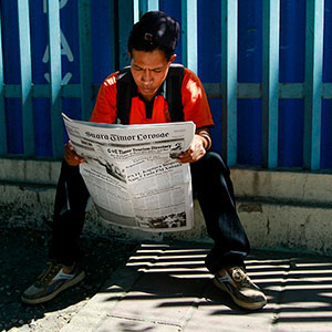 东帝汶首都帝力街头，一名正在阅读报纸的青年男子。图片/Martine Perret